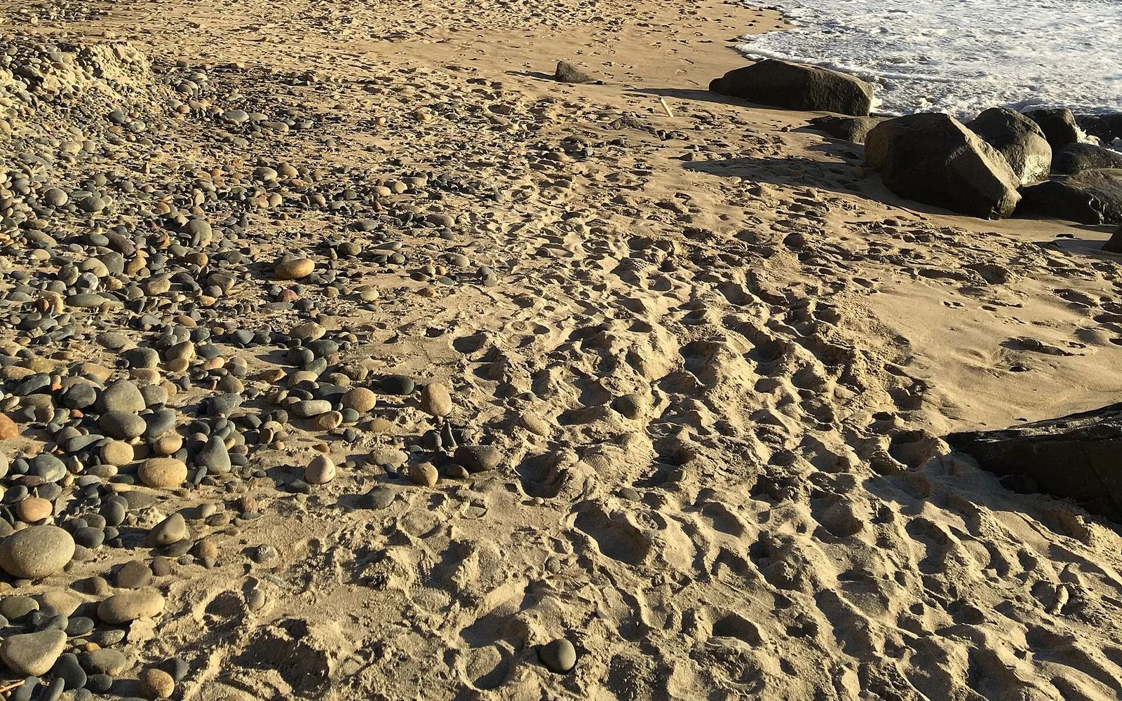 Sand, pebbles and shoreline rocks at Carlsbad State Beach.